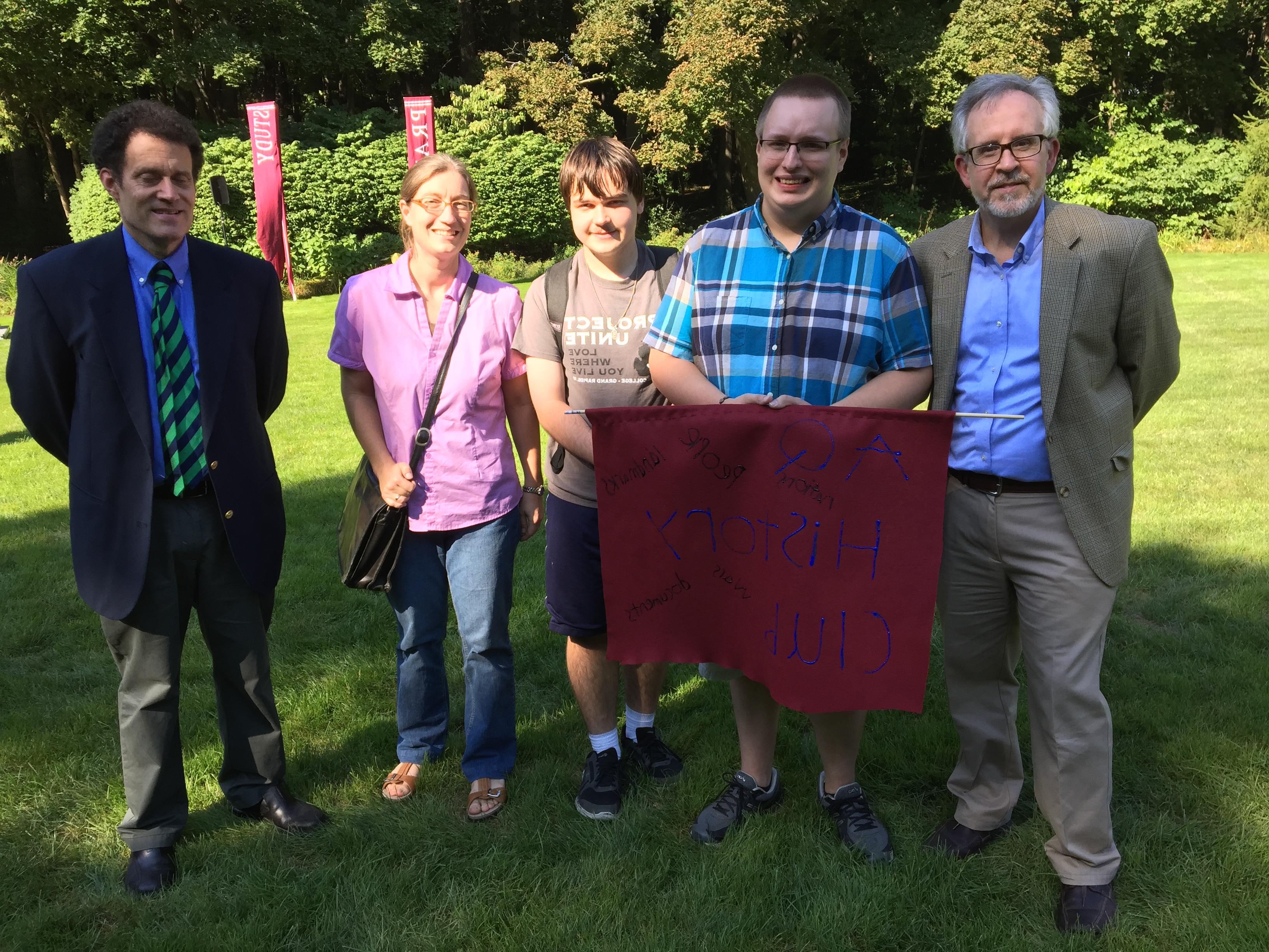 people holding an "AQ History Club" poster