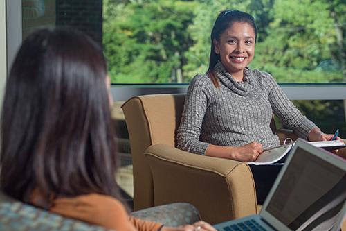 two students in arm chairs talking